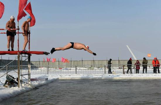 2018年1月23日，冬泳爱好者跃入哈尔滨松花江上的冬泳场。新华社记者王建威摄